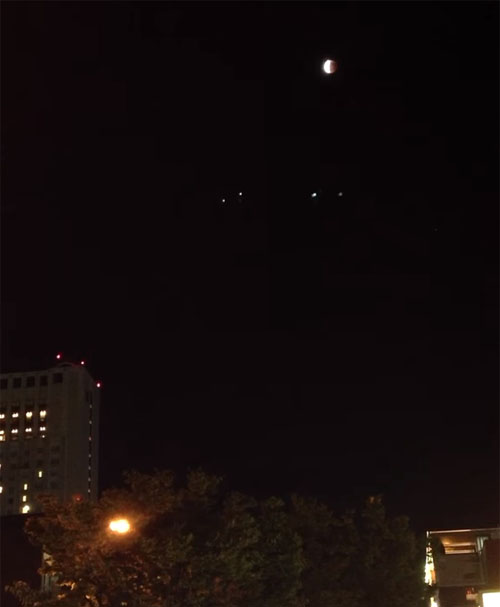 北九州市の街の上空に出現している皆既月食とUFOフリート